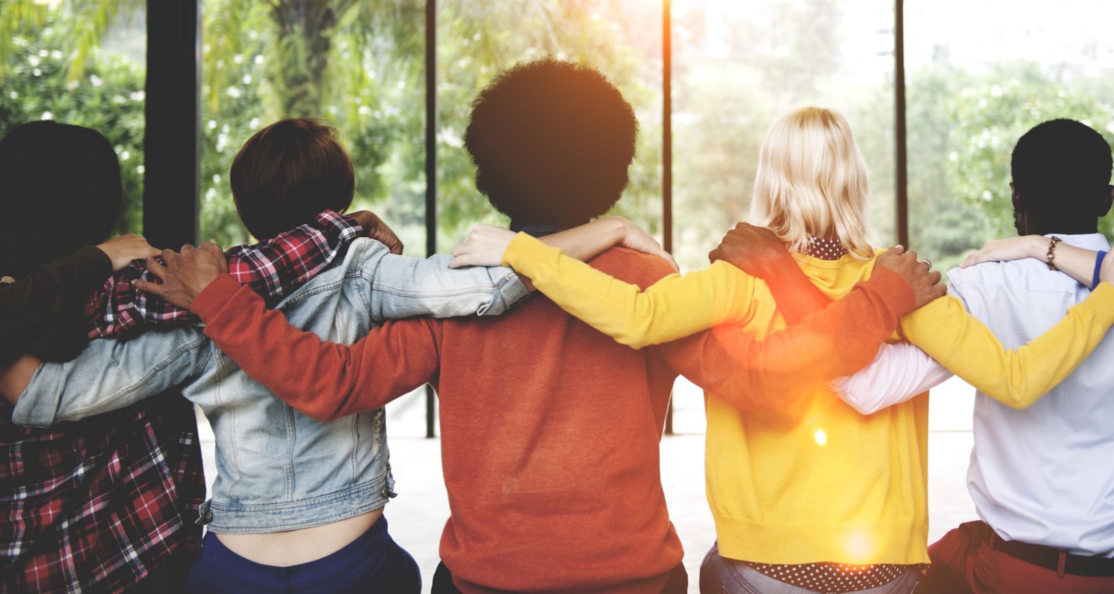 Group of people in coloured shirts with their arms round each other banner image