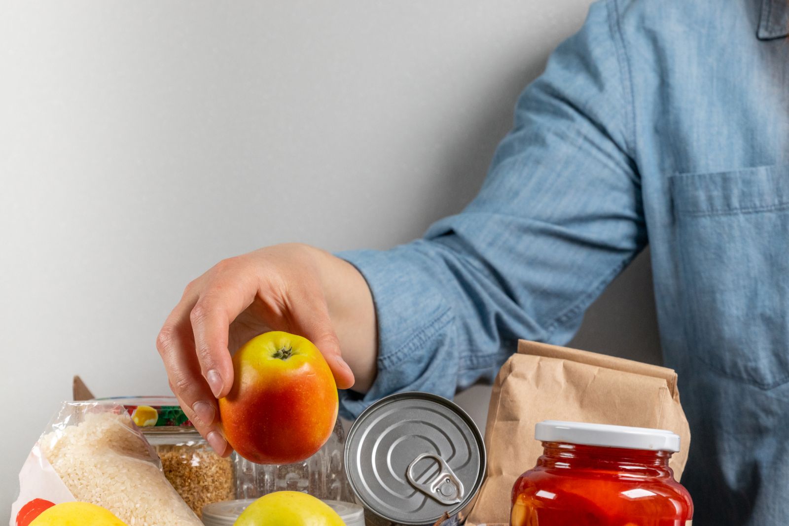 Hand picking an apple out of a donated box of food banner image