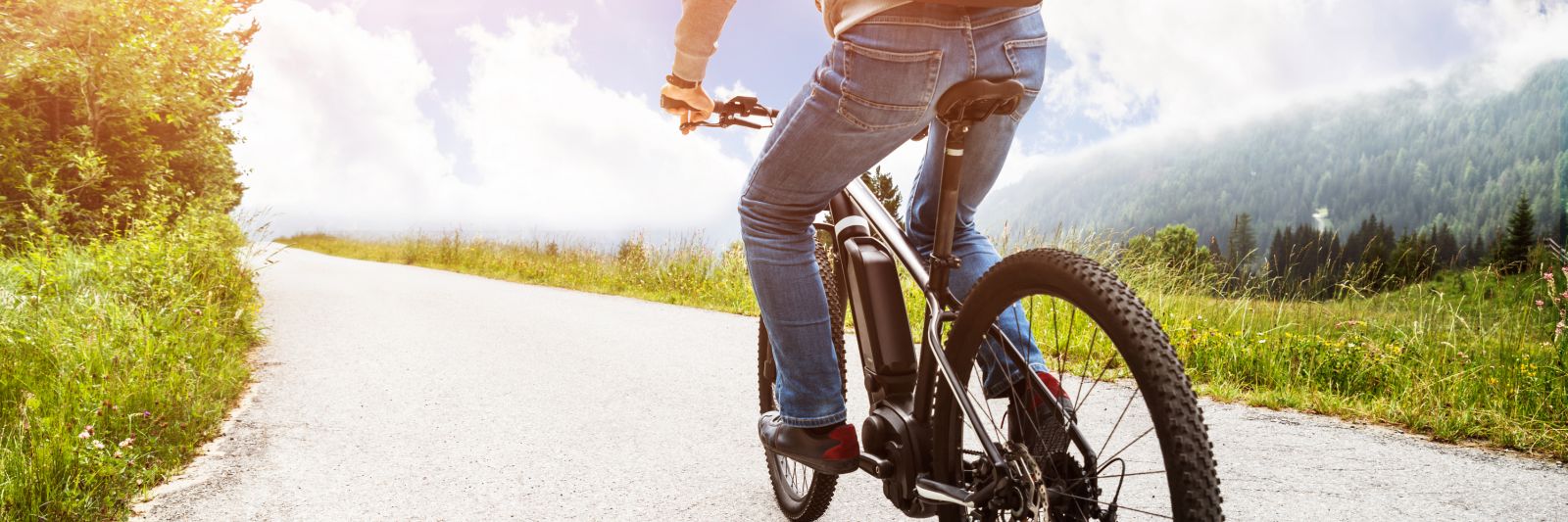 man riding an ebike on a mountain road banner image