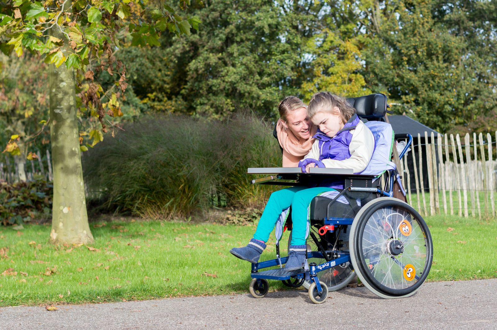 Young girl in wheelchair with mother on walking path banner image