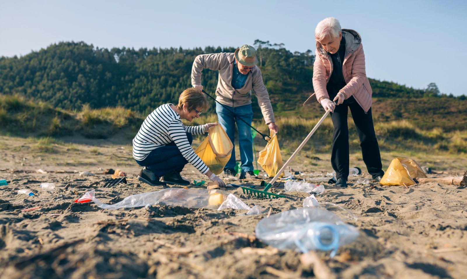 Group of older people picking litter on a beach banner image