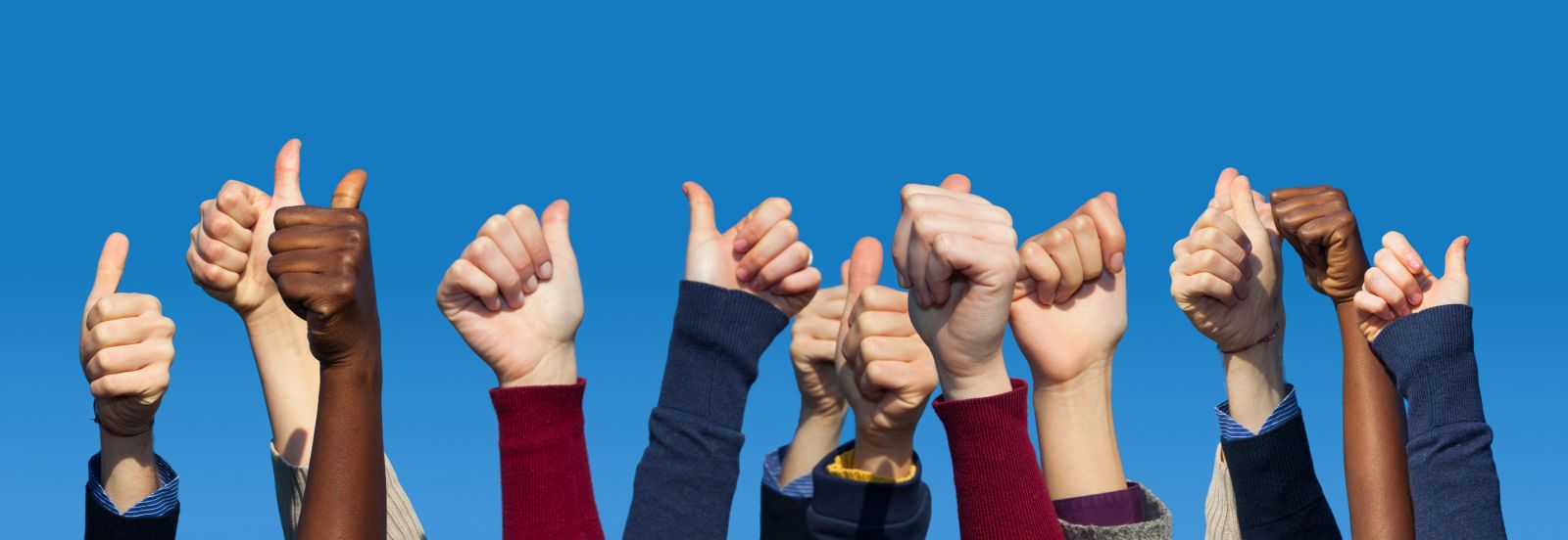 Group of hands raised in the air against the background of a blue sky banner image